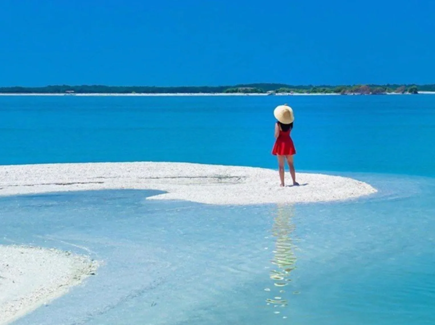 Visitor on a sandbar with blue water beyond